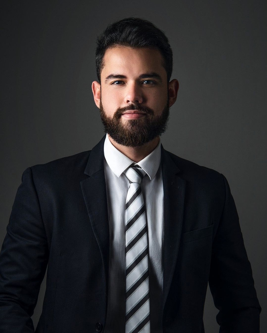Retrato de Renan Klautau, de terno escuro e gravata listrada